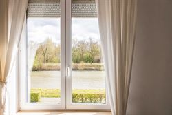 Wonen tussen water en open ruimte. Deze halfopen woning in de Koning Leopoldstraat 71 in Lovendegem kijkt vooraan uit op het Schipdonkkanaal en achter...