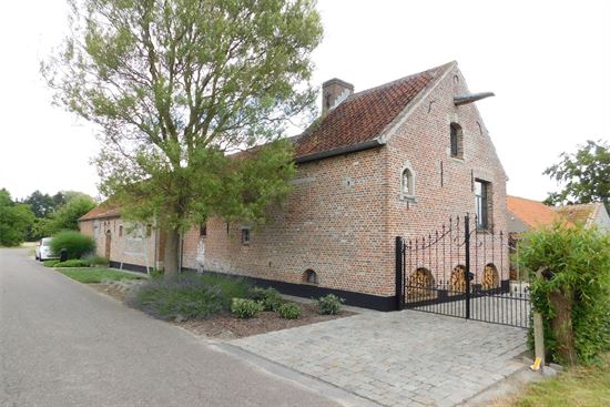 Totaal gerenoveerde langgevelhoeve met 2 bijgebouwen temidden van uitgestrekte velden.