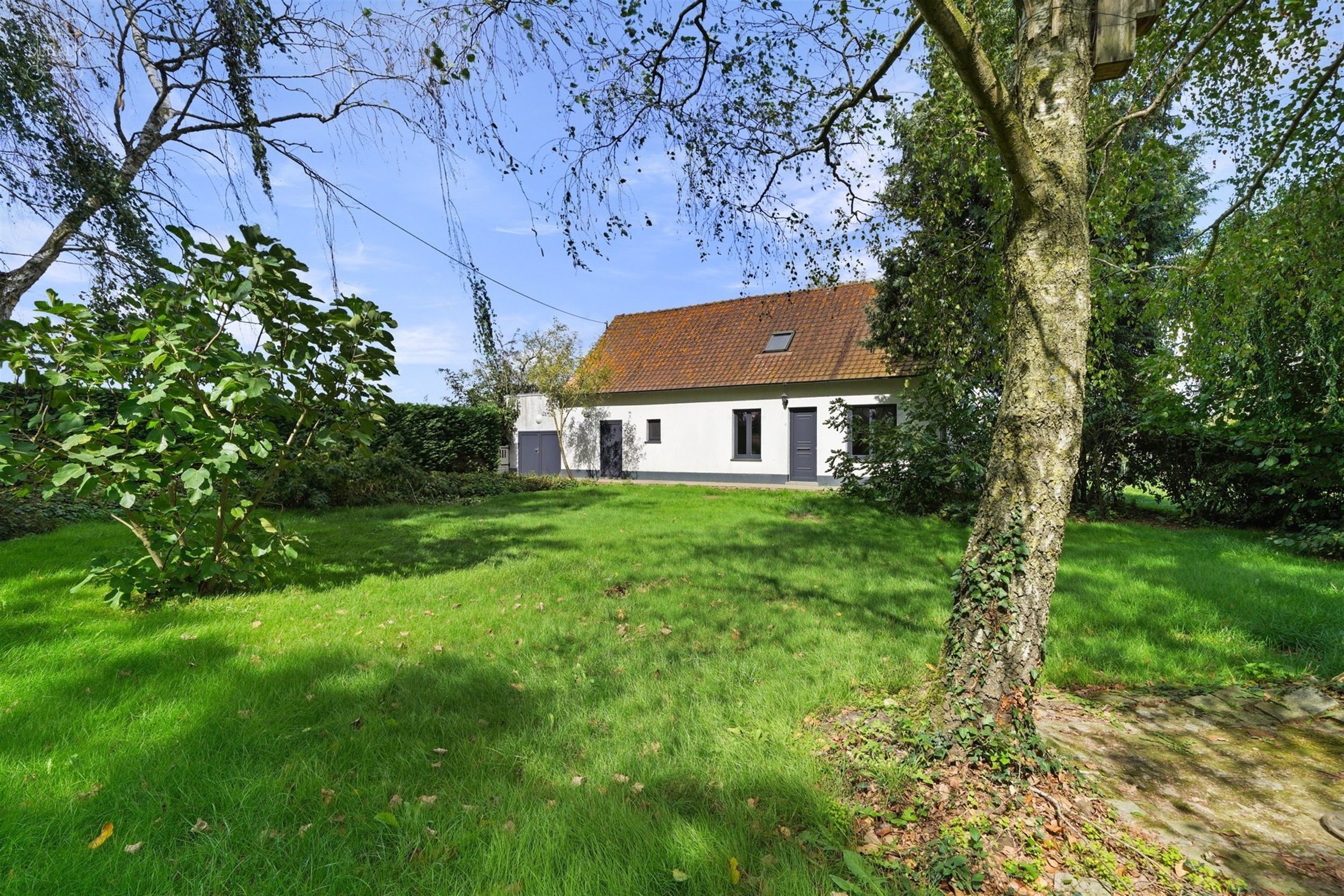 Charmante gelijkvloerse woning, iets terugliggend van een landweggetje, gebouwd op een perceel van ca. 1900 m².
Bestaat uit een woonkamer, een eetkam...